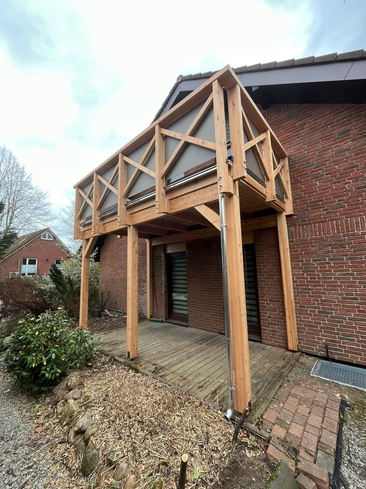 Neuer Holzbalkon an einem Klinkerhaus mit Holzstützen