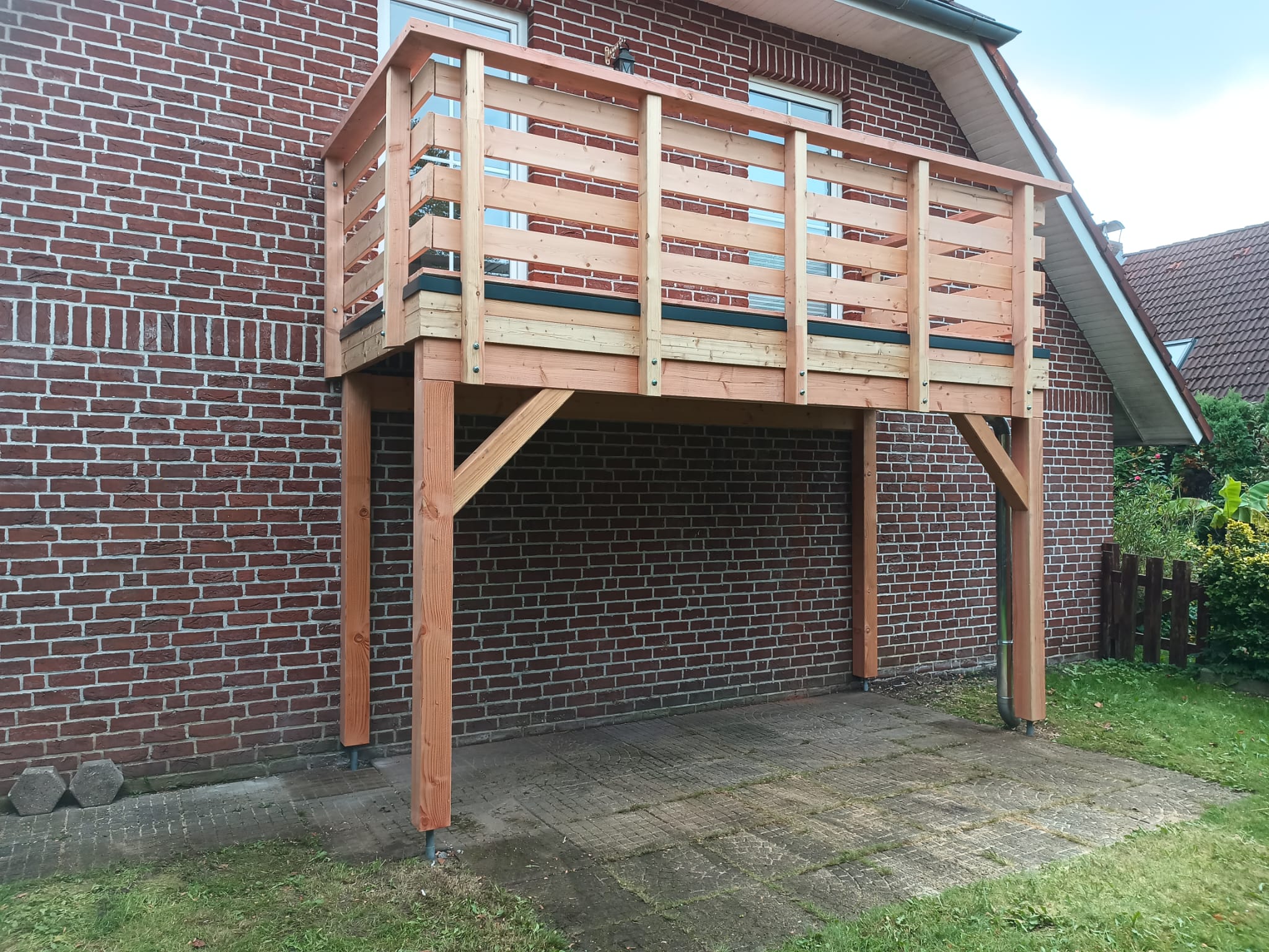 Angebauter Holzbalkon mit waagerechtem Geländer an einem Klinkerhaus