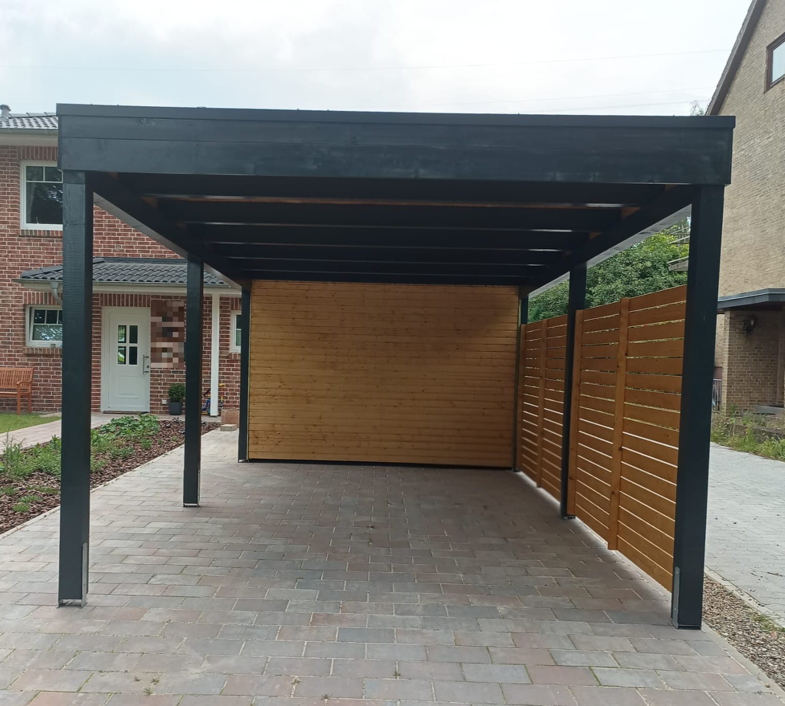 Carport in Anthrazit an einem Klinker-Reihenhaus mit Sichtschutzwand