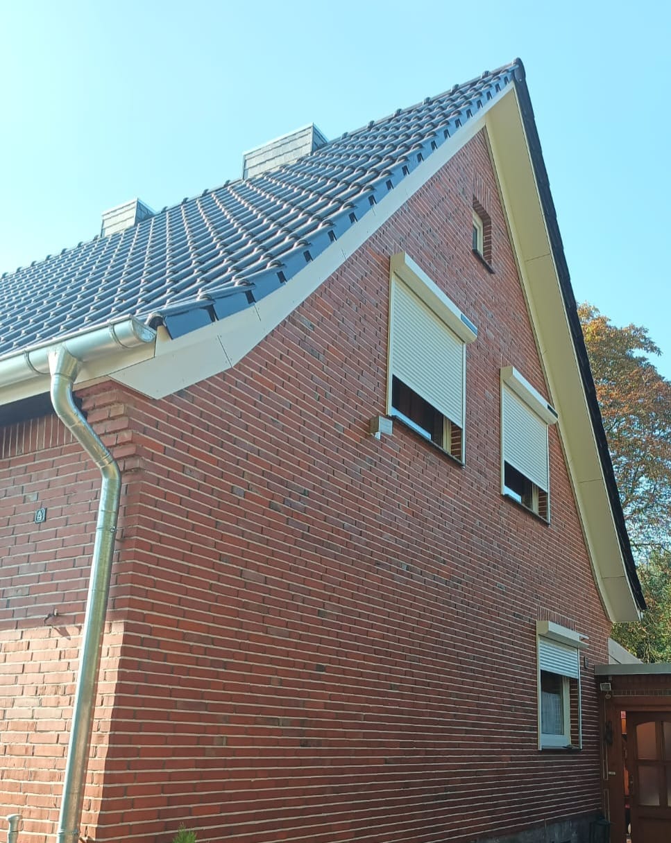 Neu gedecktes Satteldach mit Dachrinne an einem Backsteinhaus