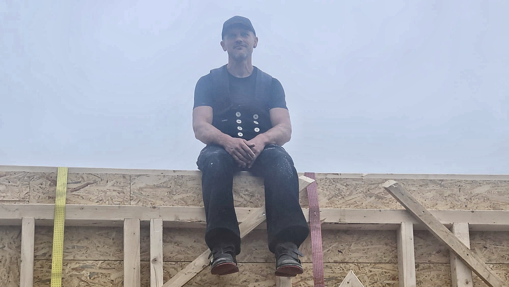 Sebastian Cord sitzt oben auf dem fertig aufgerichteten Dachstuhl