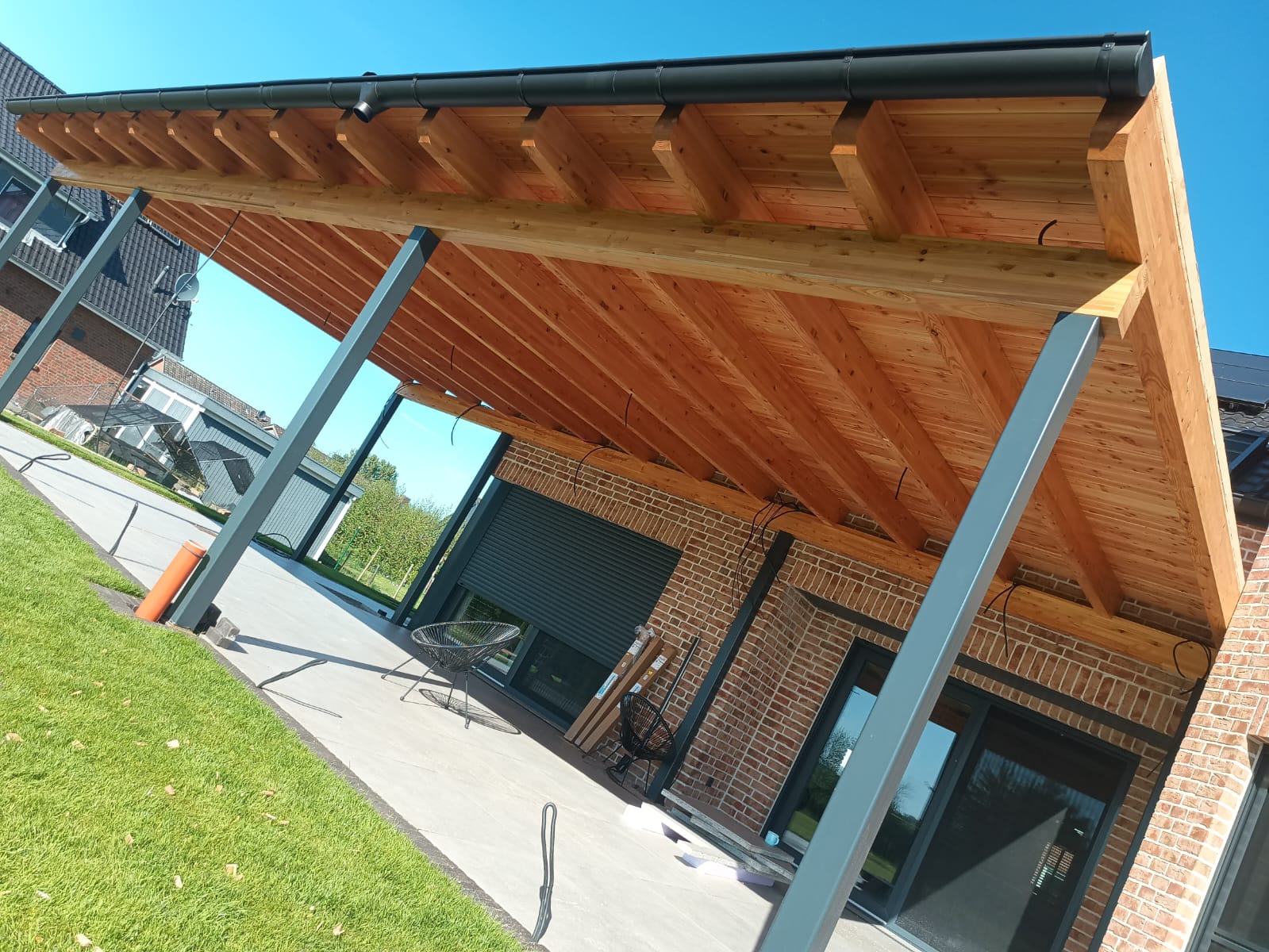 Unteransicht einer Holz-Terrassenüberdachung mit Sparren vor blauem Himmel